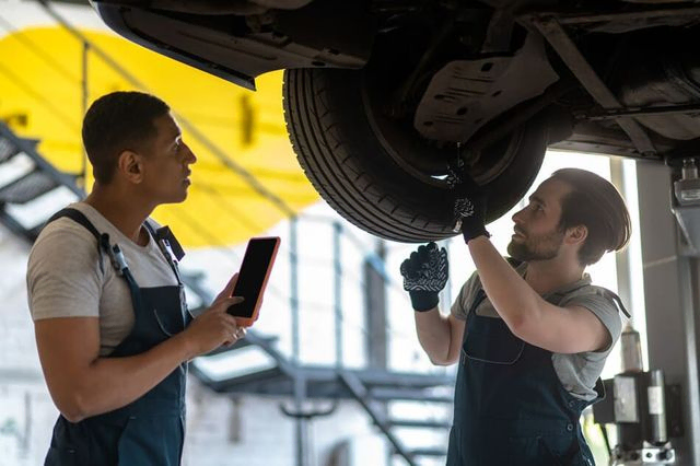 mecánicos reparando coche en foso